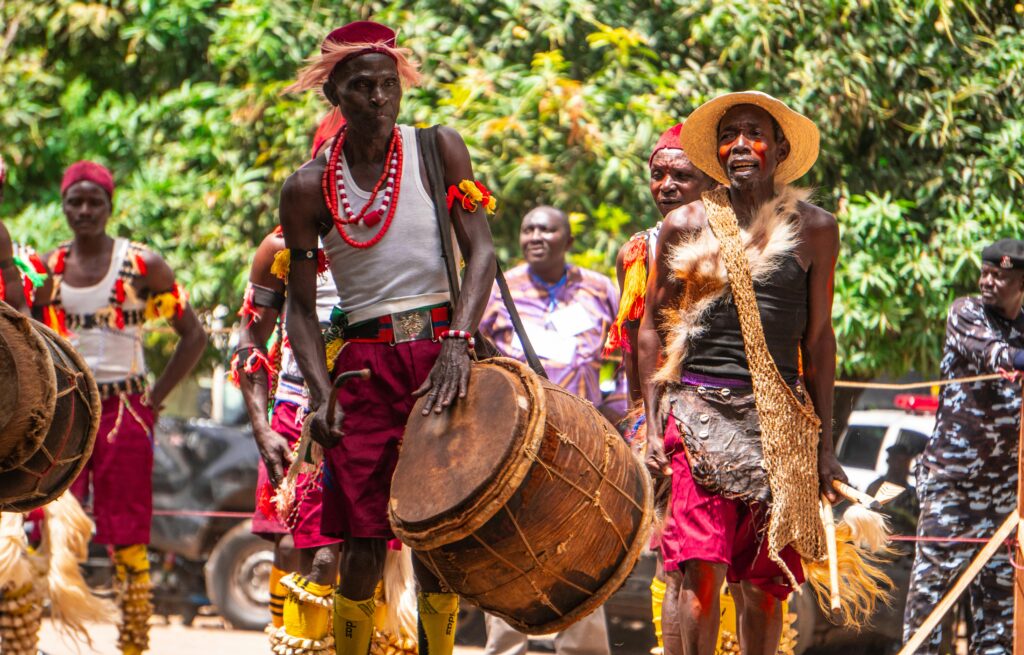 pexels-photo-27291184-27291184 Group of African men in traditional attire performing with drums during a vibrant outdoor cultural festival.