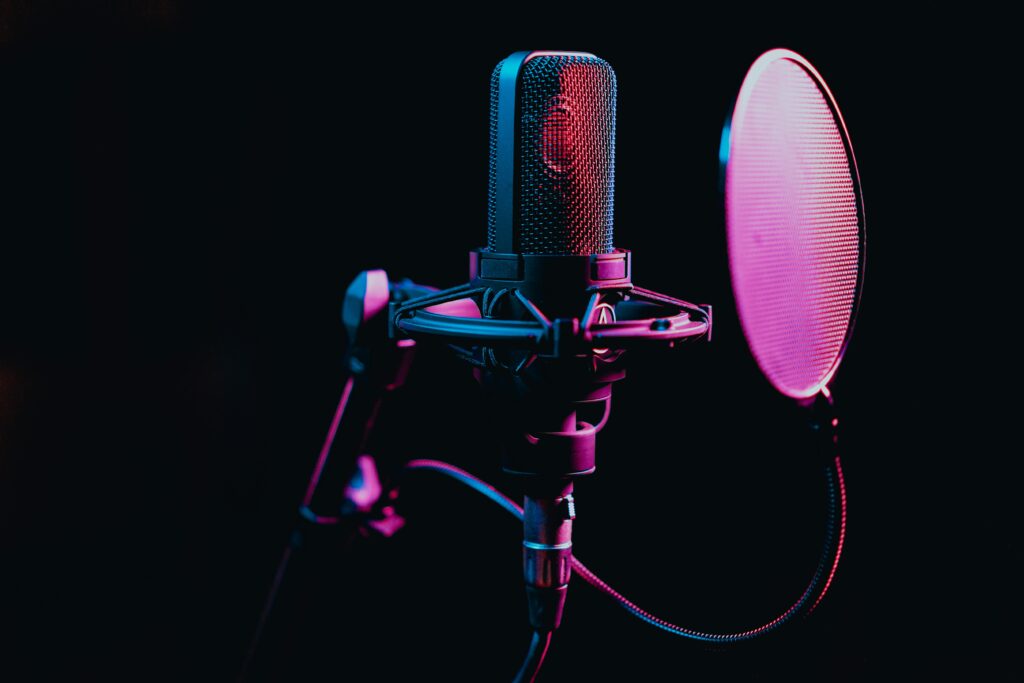 pexels-photo-7586662-7586662 Close-up image of a condenser microphone with a pop filter in a studio setting, featuring atmospheric lighting.